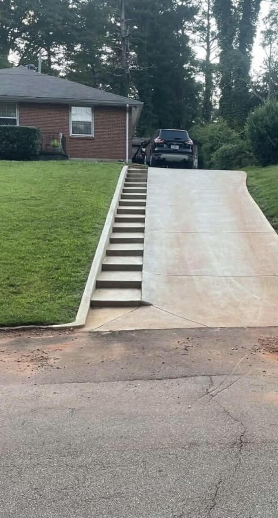 Fresh concrete driveway with a run of integrated steps up a sloped lawn